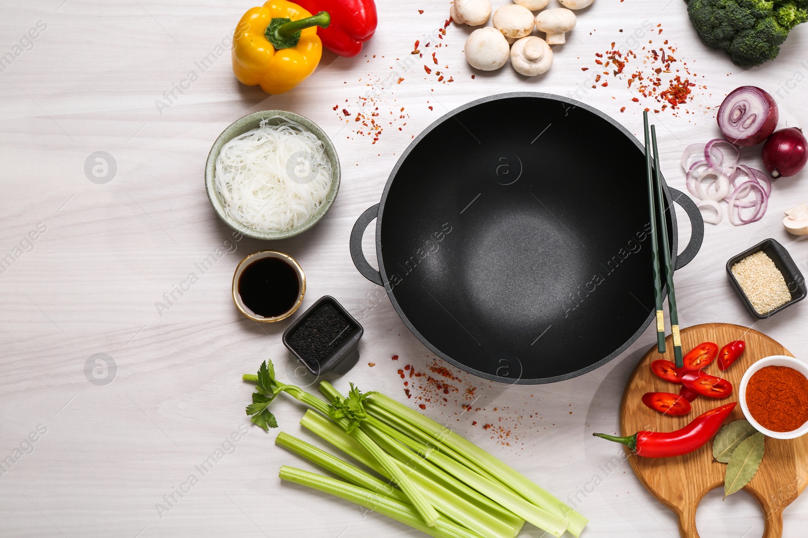 Photo of Wok, chopsticks and different products on white wooden table, flat lay. Space for text