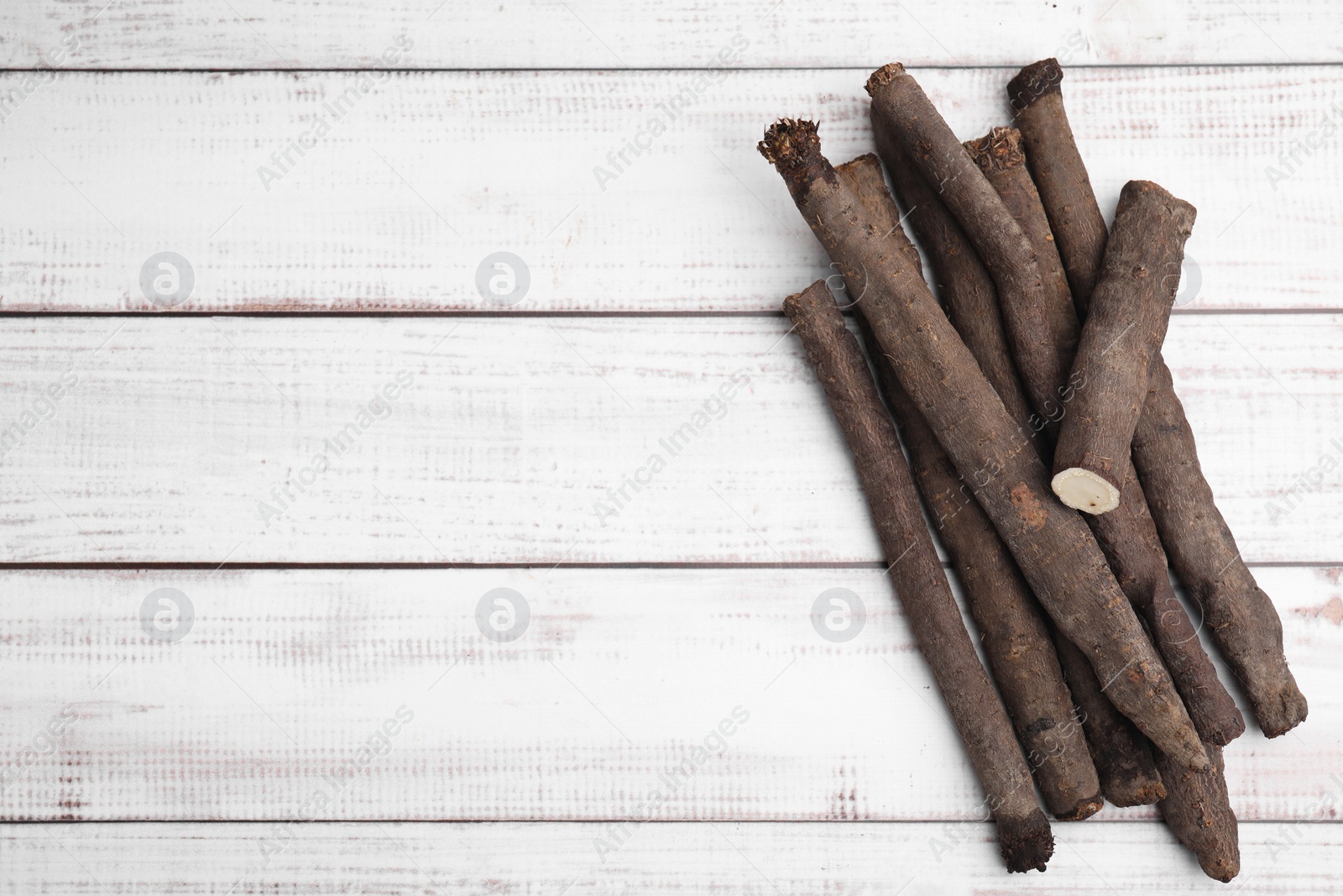 Photo of Raw salsify roots on white wooden table, flat lay. Space for text