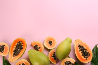 Photo of Fresh ripe papaya fruits with green leaves on pink background, flat lay. Space for text