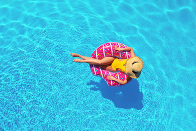 Young woman with inflatable ring in swimming pool, top view