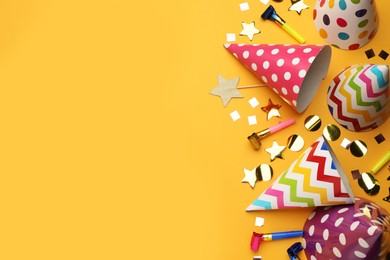 Photo of Flat lay composition with party hats and other festive items on orange background. Space for text