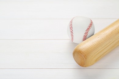 Photo of Baseball bat and ball on white wooden table, above view with space for text. Sports equipment