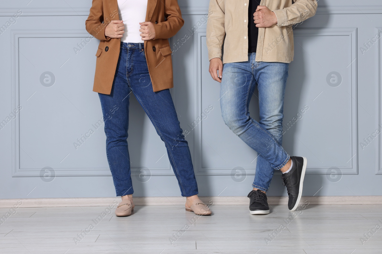 Photo of People in stylish jeans near light grey wall indoors, closeup