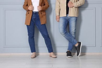 Photo of People in stylish jeans near light grey wall indoors, closeup