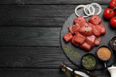 Photo of Raw beef meat and different ingredients for cooking delicious goulash on black wooden table, flat lay. Space for text