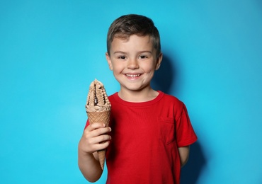 Photo of Adorable little boy with delicious ice cream against color background