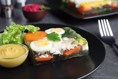 Photo of Delicious fish aspic served on black table, closeup