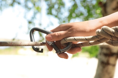 Photo of Woman using screw lock carabiner during training outdoors, closeup