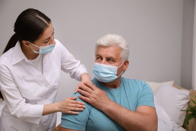 Doctor taking care of senior man with protective mask at nursing home