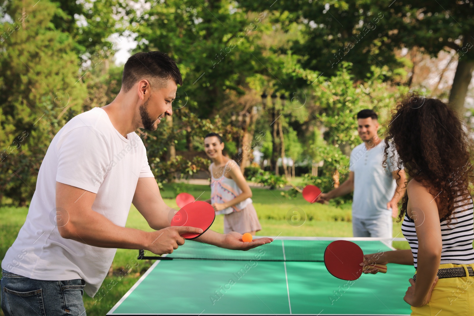 Photo of Friends playing ping pong outdoors on summer day