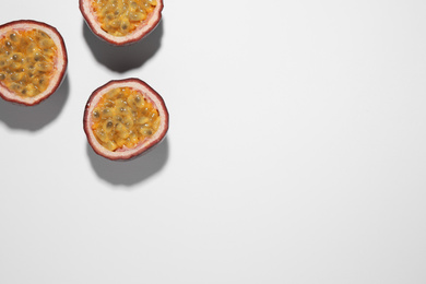 Photo of Halves of passion fruits (maracuyas) on white background, flat lay. Space for text