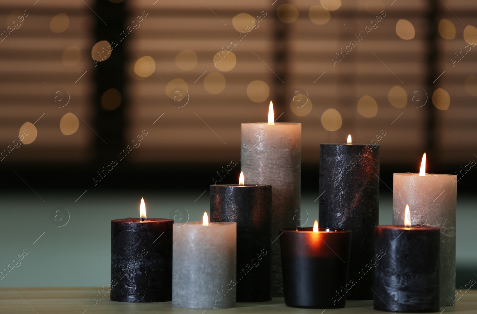 Photo of Beautiful burning candles on wooden table against festive lights. Space for text