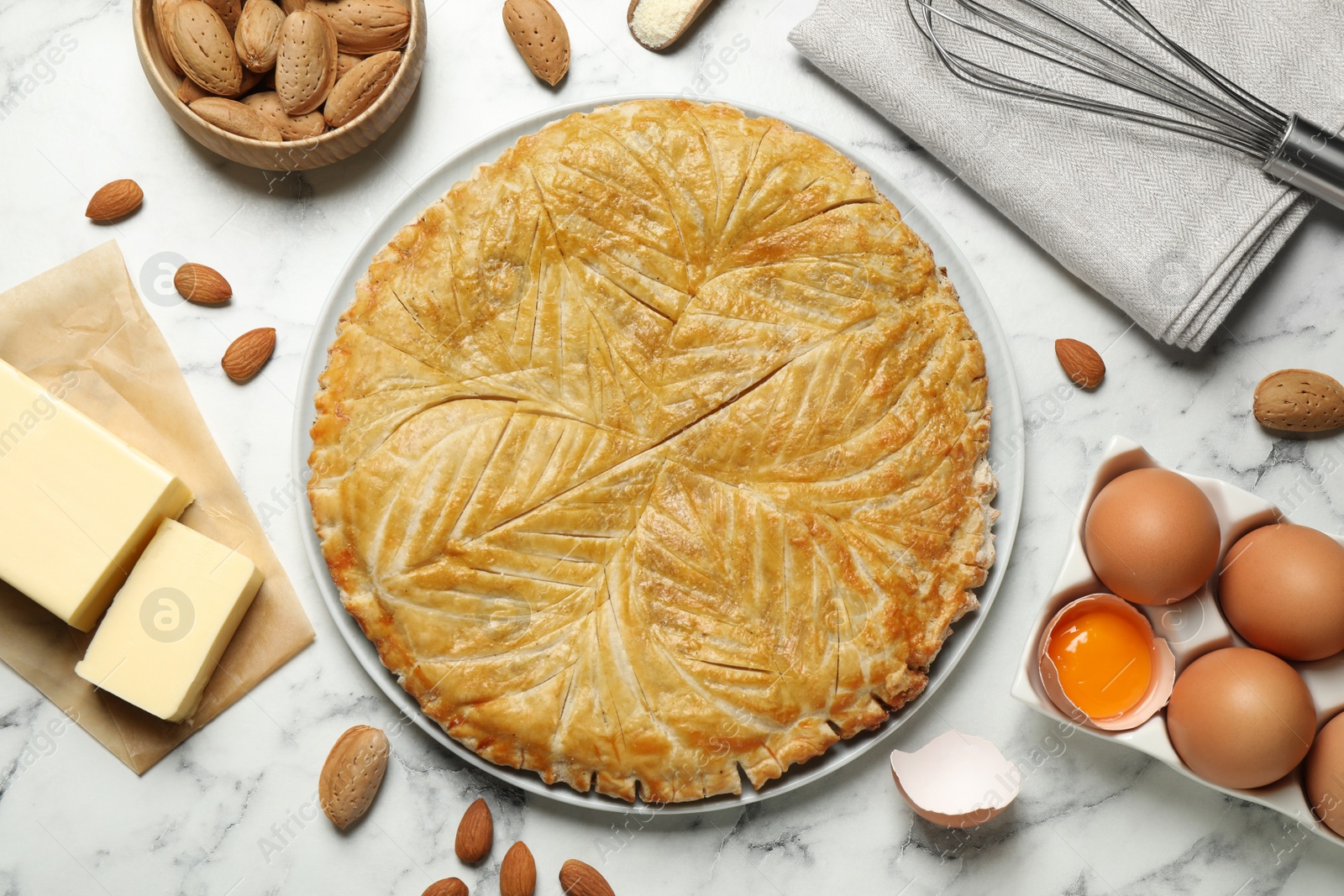 Photo of Traditional galette des rois and ingredients on white marble table, flat lay