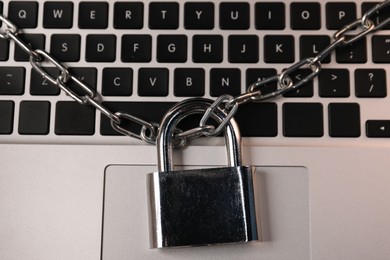 Photo of Cyber security. Padlock with chain on laptop, top view