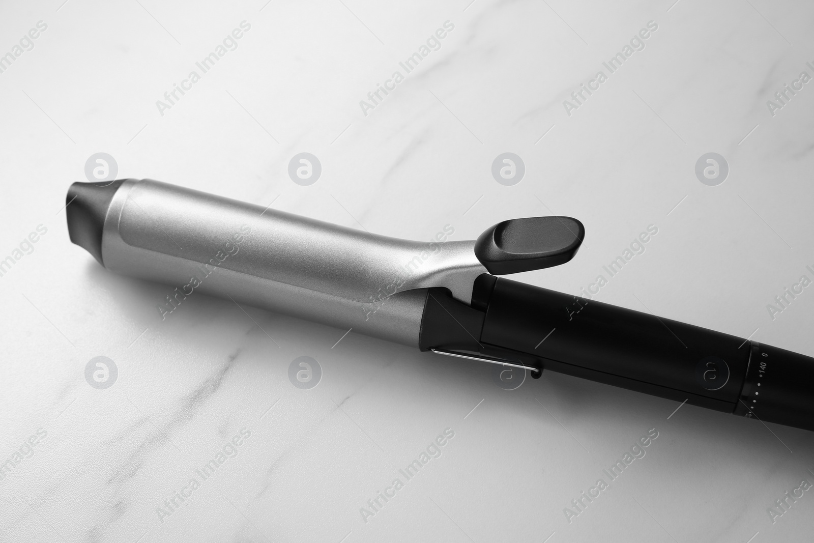 Photo of Hair curling iron on white marble background