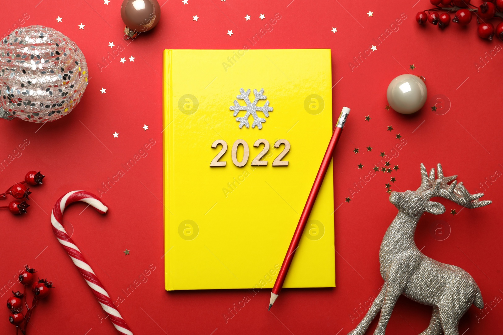 Photo of Yellow planner and Christmas decor on red background, flat lay. Planning for 2022 New Year