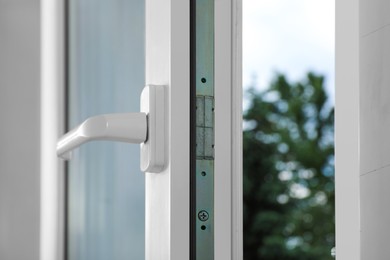 Photo of Open window with white plastic frame indoors, closeup