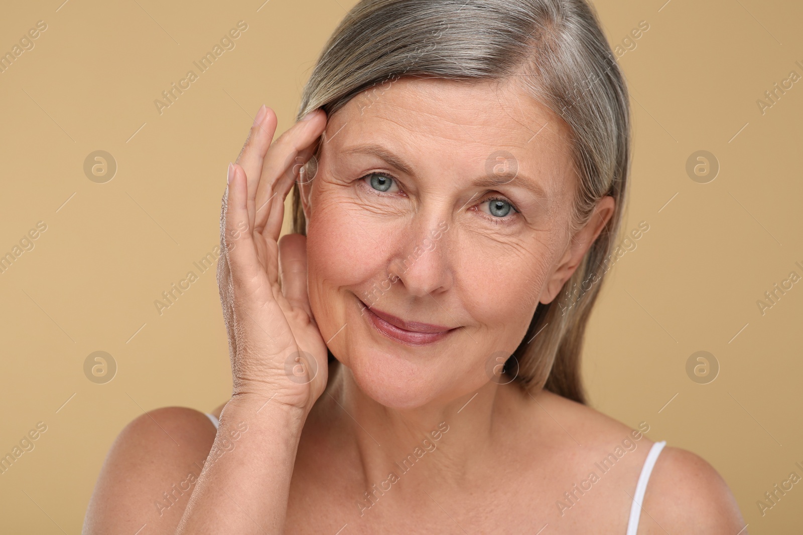 Photo of Portrait of senior woman with aging skin on beige background. Rejuvenation treatment