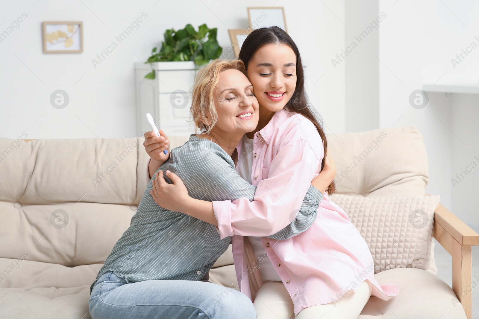 Photo of Happy pregnant woman spending time with her mother at home. Grandparents' reaction to future grandson