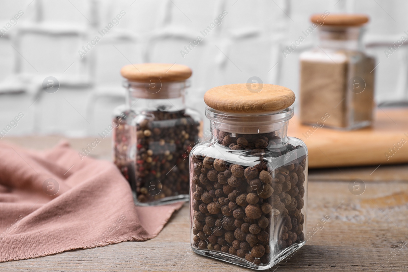 Photo of Glass jars with peppercorns on wooden table