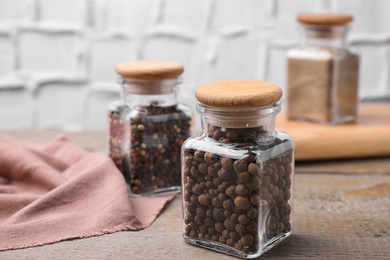 Photo of Glass jars with peppercorns on wooden table