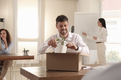 Photo of New coworker unpacking box with personal items at workplace in office