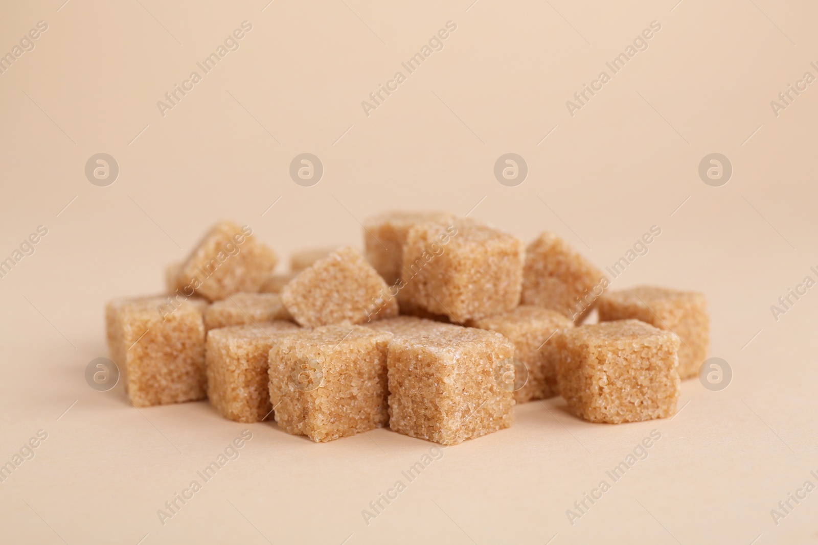 Photo of Pile of brown sugar cubes on beige background