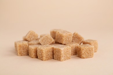 Photo of Pile of brown sugar cubes on beige background