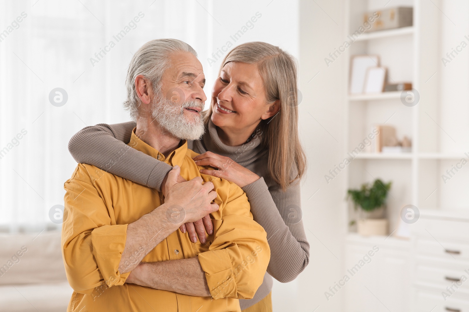 Photo of Portrait of affectionate senior couple at home, space for text