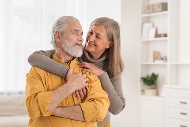 Portrait of affectionate senior couple at home, space for text