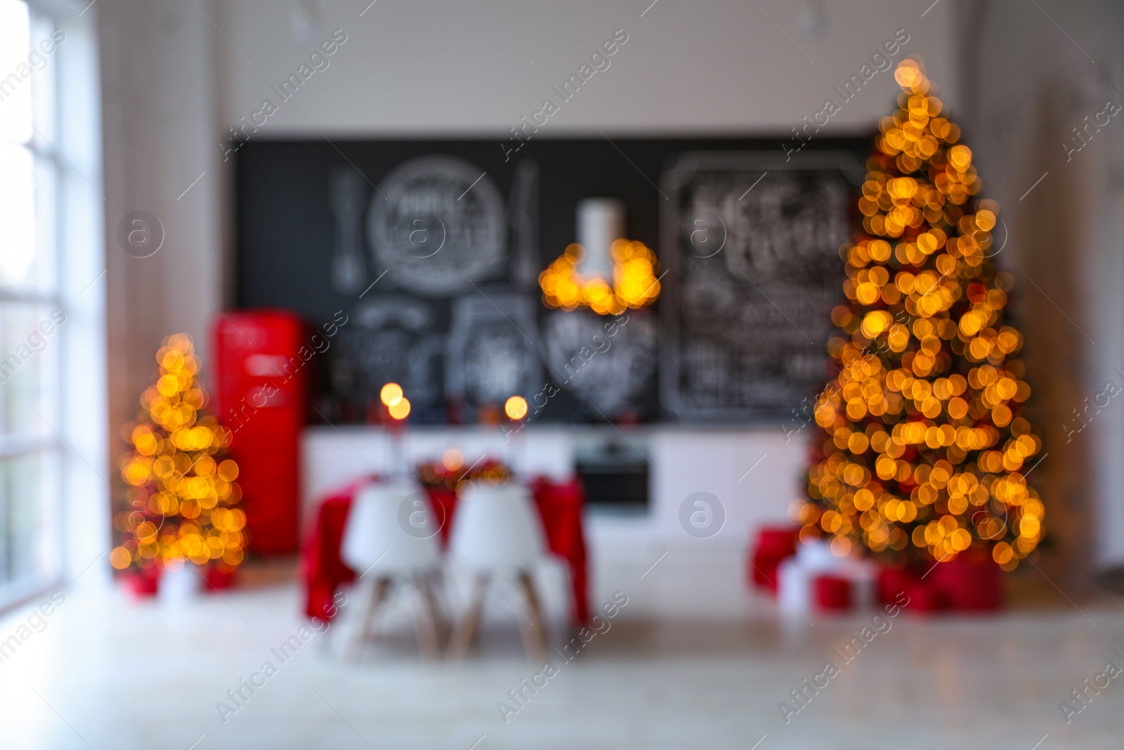 Photo of Stylish kitchen interior with festive table and  decorated Christmas trees, blurred view