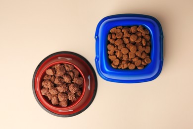 Dry and wet pet food in feeding bowls on beige background, flat lay