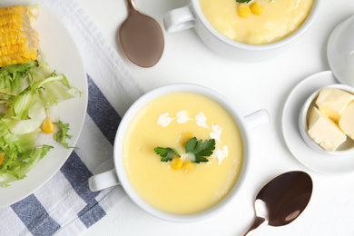 Photo of Delicious corn cream soup served on white table, flat lay