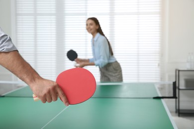 Business people playing ping pong in office, focus on tennis racket