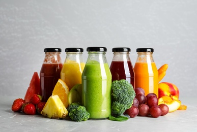 Bottles of delicious juices and fresh fruits on marble table