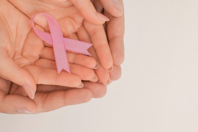 Couple holding pink ribbon on white background, top view with space for text. Breast cancer awareness