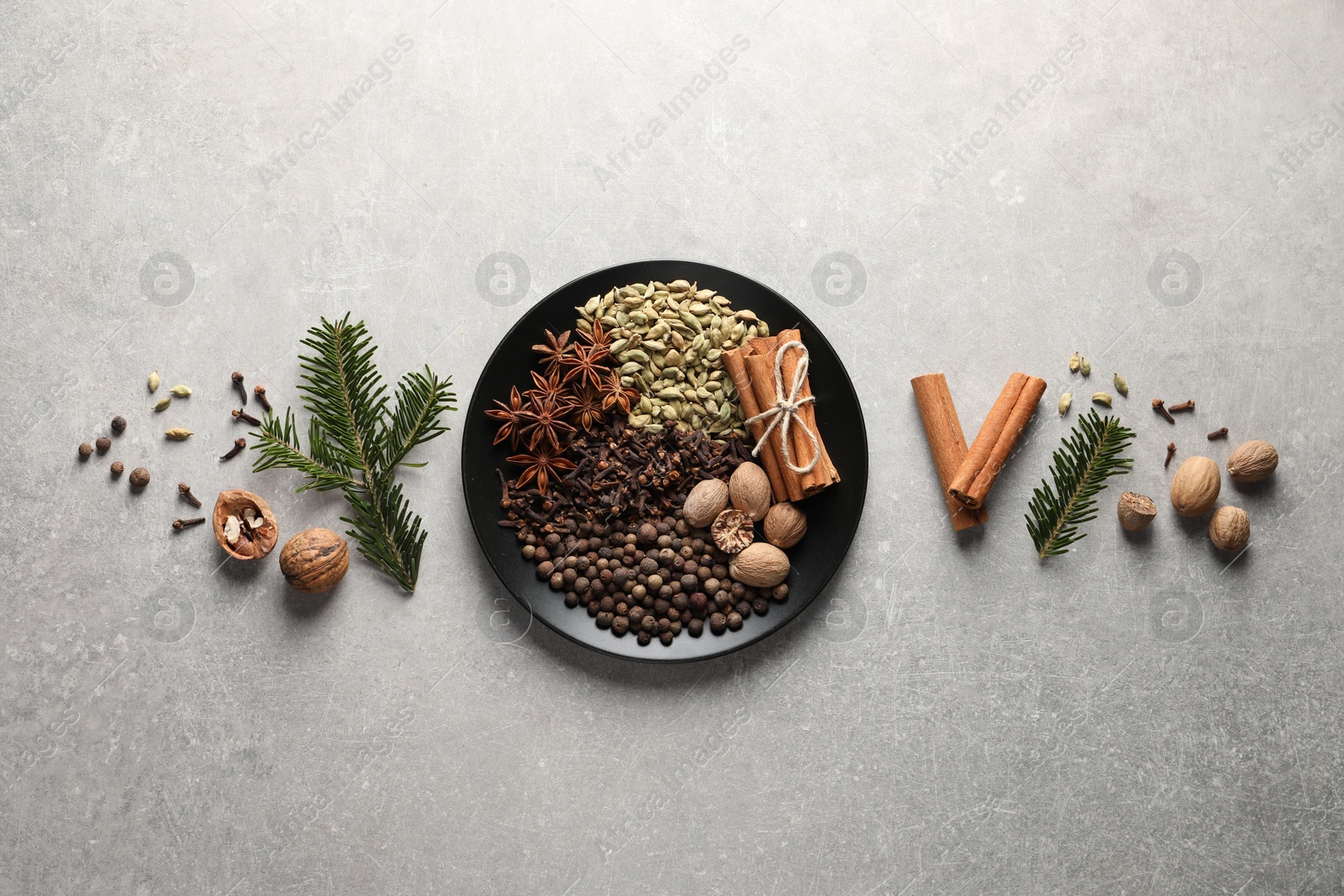 Photo of Different spices, nuts and fir branches on light gray textured table, flat lay