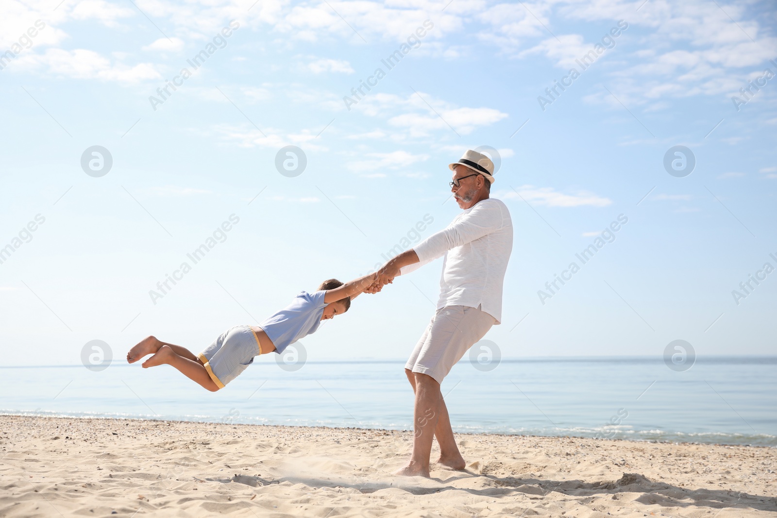 Photo of Grandfather playing with little boy on sea beach