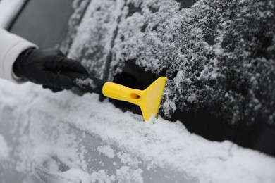 Man cleaning snow from car outdoors, closeup