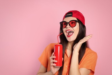 Photo of Excited young woman in stylish sunglasses holding tin can with beverage on pink background. Space for text