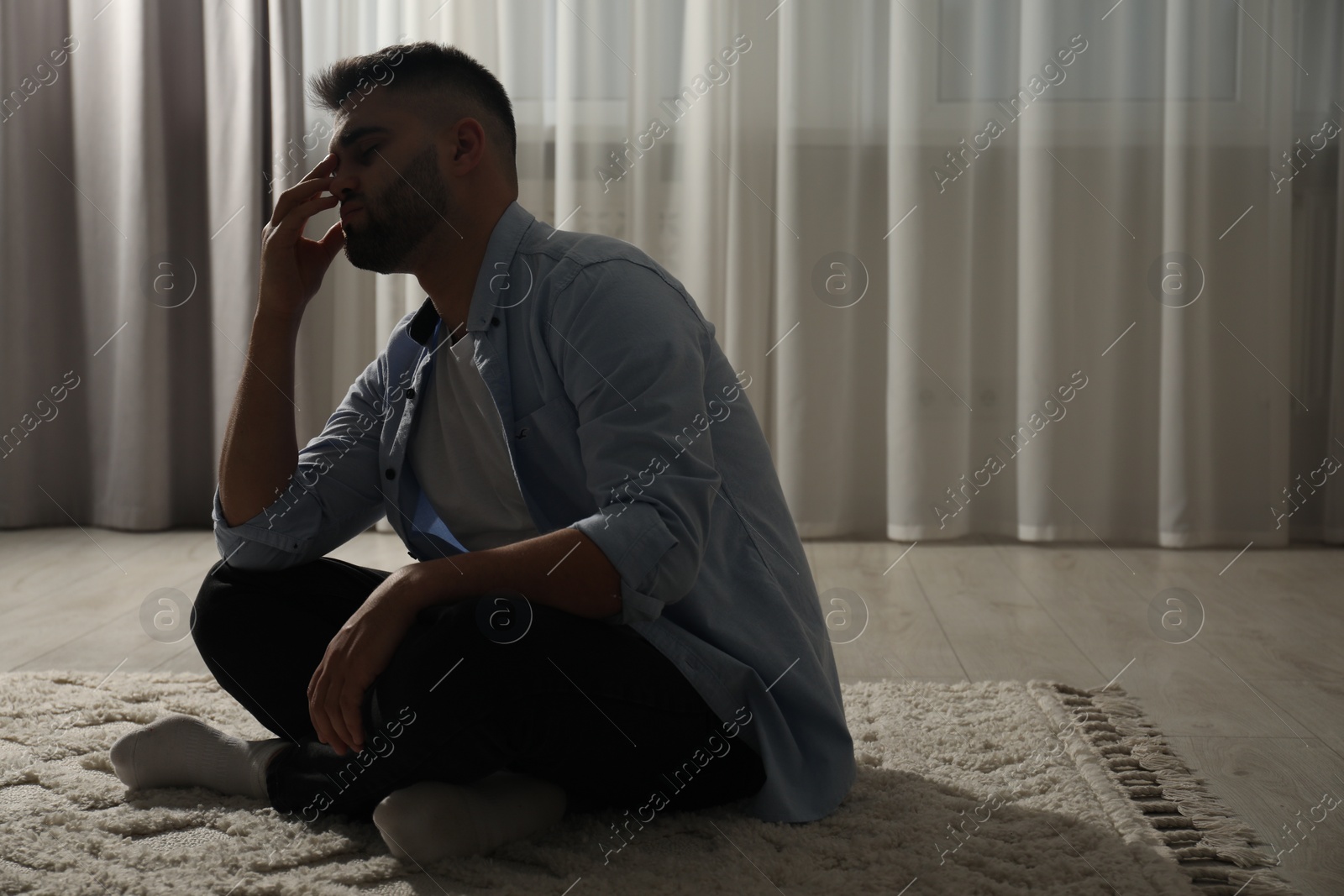 Photo of Sad man sitting on floor near window. Space for text