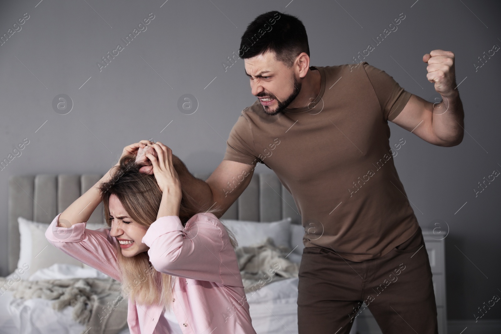 Photo of Man abusing scared woman at home. Domestic violence