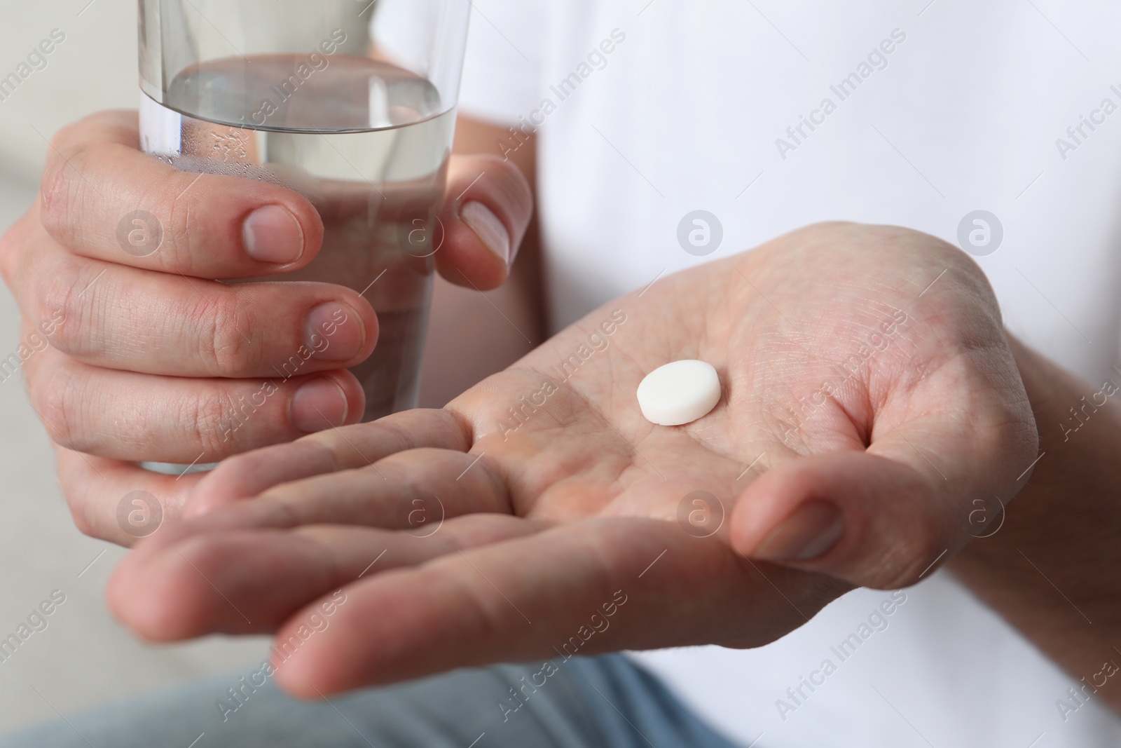 Photo of Man with glass of water and pill, closeup view