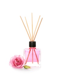 Photo of Aromatic reed air freshener and rose on white background