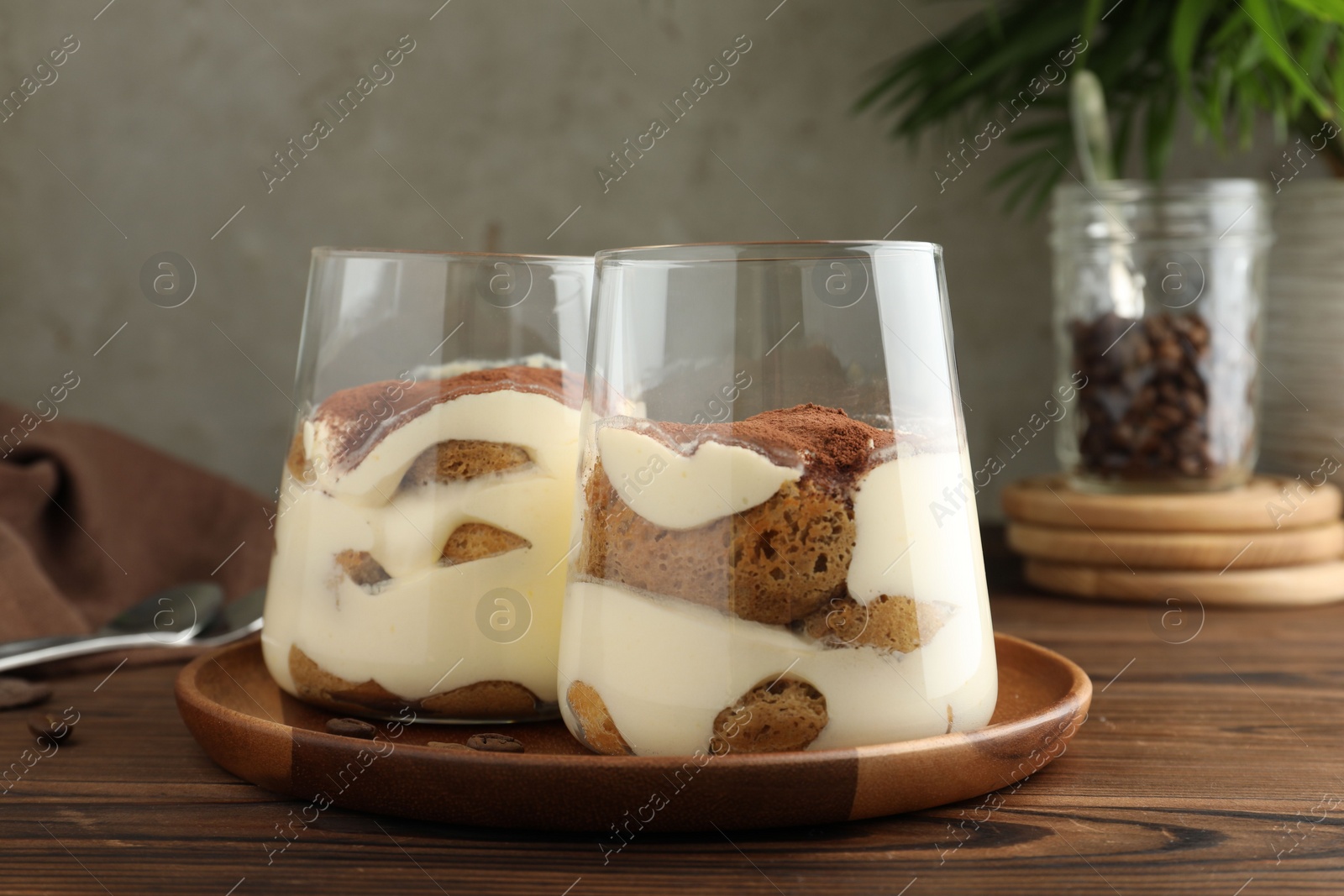 Photo of Delicious tiramisu in glasses on wooden table