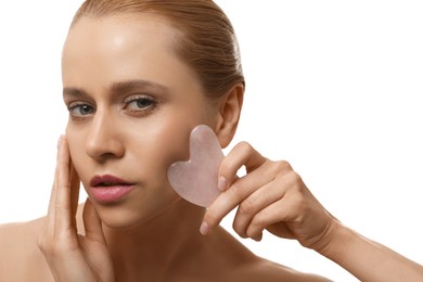 Photo of Beautiful young woman doing facial massage with gua sha tool on white background, closeup