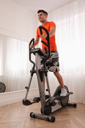 Man using modern elliptical machine at home