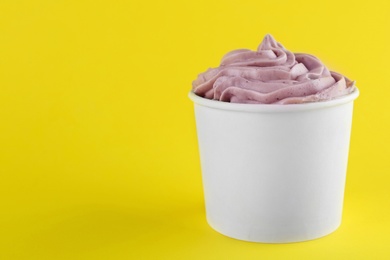 Cup with tasty frozen yogurt on yellow background. Space for text