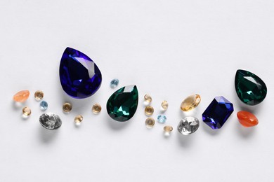 Different beautiful gemstones for jewelry on white background, top view