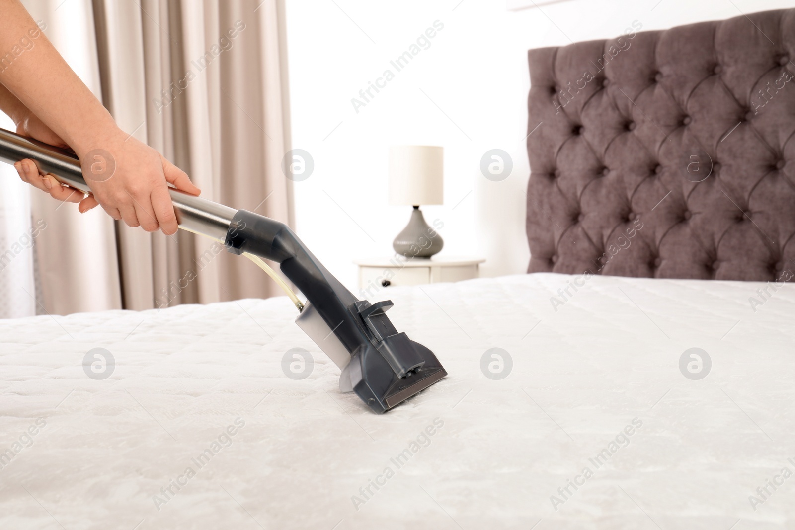 Photo of Woman disinfecting mattress with vacuum cleaner, closeup. Space for text